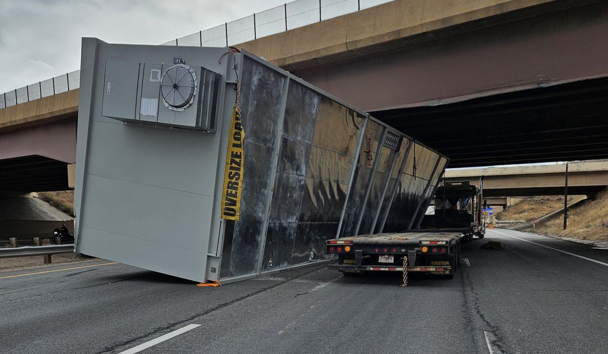 NextImg:Semi truck with an oversized construction trailer stuck under Colorado bridge