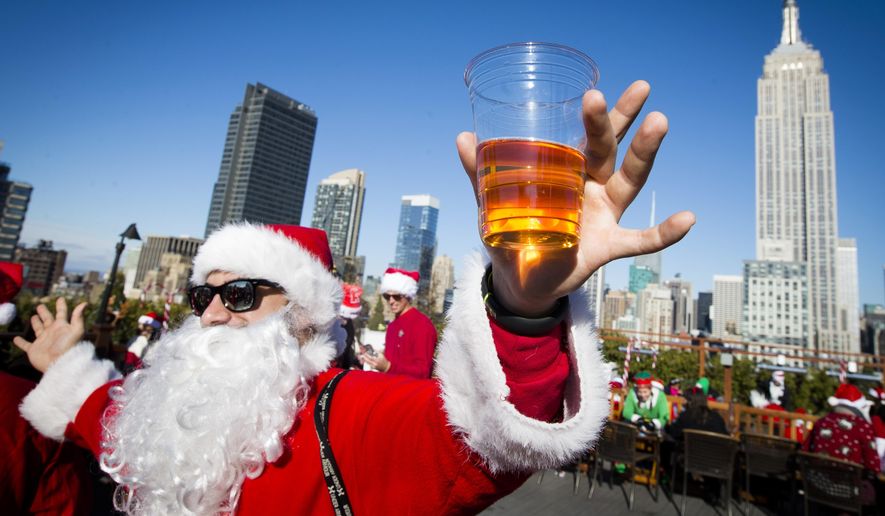 A man dressed as Santa Claus holds a beer as he and others participate in SantaCon on a rooftop bar Saturday, Dec. 13, 2014, in New York. Thousands of people dressed as jolly Old St. Nick have descended on New York City for the annual SantaCon charity pub crawl. The booze-fueled stroll through Manhattan kicked off Saturday morning, Dec. 9, 2023, in bars in midtown. (AP Photo/John Minchillo, File)