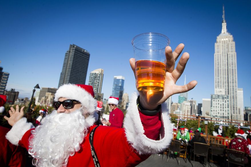 A man dressed as Santa Claus holds a beer as he and others participate in SantaCon on a rooftop bar Saturday, Dec. 13, 2014, in New York. Thousands of people dressed as jolly Old St. Nick have descended on New York City for the annual SantaCon charity pub crawl. The booze-fueled stroll through Manhattan kicked off Saturday morning, Dec. 9, 2023, in bars in midtown. (AP Photo/John Minchillo, File)