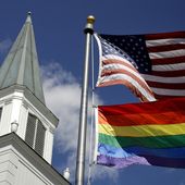 A gay pride rainbow flag flies along with the U.S. flag in front of the Asbury United Methodist Church in Prairie Village, Kan., on April 19, 2019. (AP Photo/Charlie Riedel) **FILE**