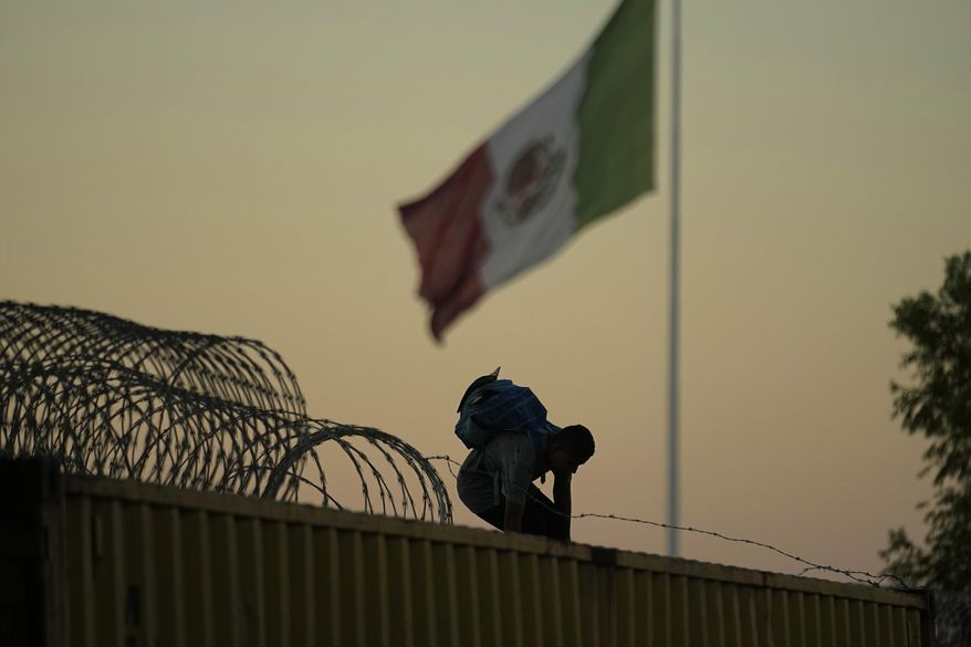 A migrant who crossed the Rio Grande from Mexico to the U.S. works their way through and over concertina wire and box car barriers, Friday, Sept. 22, 2023, in Eagle Pass, Texas. Abbott is expected to sign into law sweeping new powers that allow police to arrest migrants who cross the border illegally and give local judges authority to order them to leave the country. (AP Photo/Eric Gay) **FILE**