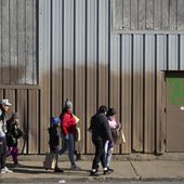 Immigrants walk down the sidewalk outside a shelter in the Pilsen neighborhood of Chicago, after receiving some items Tuesday, Dec. 19, 2023. The death of a 5-year-old migrant boy and reported illnesses in other children living at the shelter has raised concerns about the living conditions and medical care provided for asylum-seekers arriving in Chicago. Four more people living in the same shelter — mostly children — were hospitalized with fevers this week. (AP Photo/Charles Rex Arbogast)