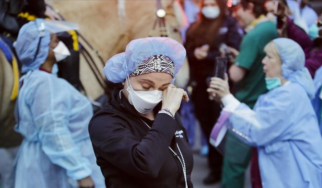 A medical worker reacts as police officers and pedestrians cheer medical workers outside NYU Medical Center in New York, April 16, 2020. Some states that stockpiled millions of masks and other personal protective equipment during the coronavirus pandemic are now throwing the items away. (AP Photo/Frank Franklin II, File)