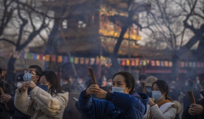 Visitors burn incense as they pray on the first day of the Lunar New Year holiday at the Lama Temple in Beijing on Jan. 22, 2023. (AP Photo/Mark Schiefelbein, File)