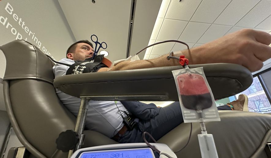 Aaron Posey, a Bloodworks Northwest executive, donates blood at the blood center&#x27;s Seattle headquarters on Dec. 14, 2023. New federal guidelines that dropped an abstinence requirement before gay men in monogamous relationships can give blood are opening a new pool of potential donors. Posey, whose own life was saved by a transfusion when he fell down a set of stairs and broken glass sliced an artery, welcomed the new guidance, saying hospitals and patients need access to a new pool of donors. (AP Photo/Manuel Valdes)
