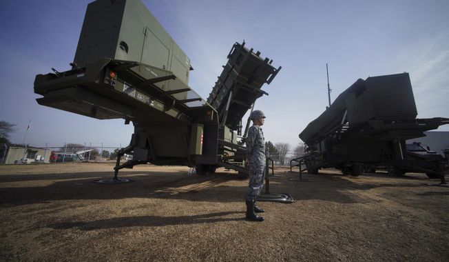FILE - A member of the Japan Ground Self-Defense Force stands guard next to a surface-to-air Patriot Advanced Capability-3 (PAC-3) missile interceptor launcher vehicle in Funabashi, east of Tokyo, on Jan. 18, 2018. Japan’s defense spending will increase more than 16% next year under a record military budget approved Friday, Dec. 22, 2023, that is intended to accelerate the deployment of long-range cruise missiles that can hit targets in China or North Korea. (AP Photo/Eugene Hoshiko, File)