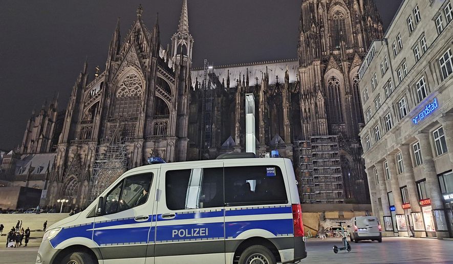 A police vehicle is parked in front of the cathedral in Cologne, Germany, Saturday, Dec. 23, 2023. Cologne police acting on indications of a possible attack searched Germany&#x27;s landmark cathedral with sniffer dogs Saturday and said worshippers attending Christmas Eve Mass would undergo security screening before being allowed in. (Sascha Thelen/dpa via AP)