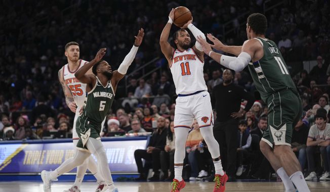 New York Knicks&#x27; Jalen Brunson (11), second from right, puts up a shot over Milwaukee Bucks&#x27; Brook Lopez, right, during the first half of an NBA basketball game, Monday, Dec. 25, 2023, in New York. (AP Photo/Seth Wenig)