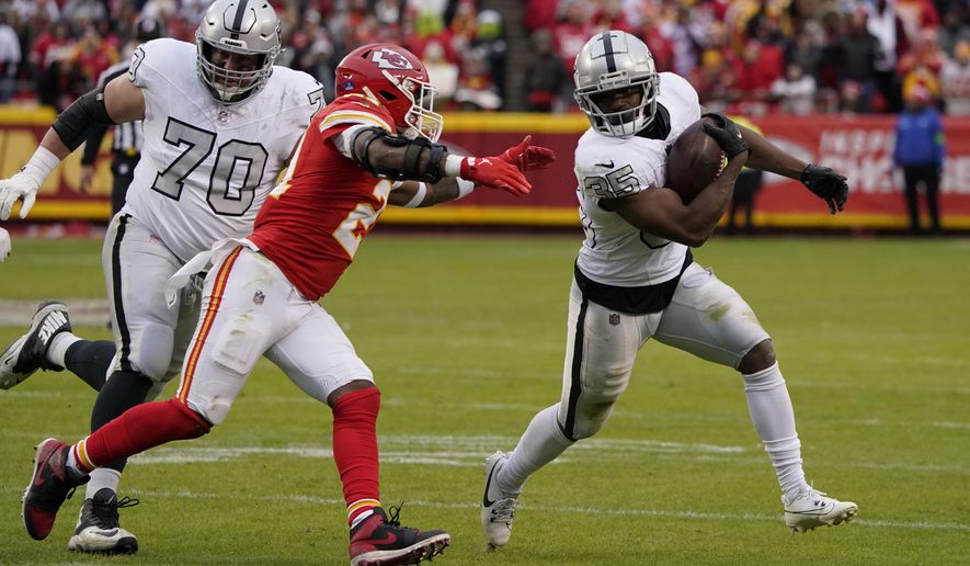 Las Vegas Raiders running back Zamir White (35) runs with the ball as Kansas City Chiefs safety Mike Edwards defends and Raiders guard Greg Van Roten looks on during the second half of an NFL football game Monday, Dec. 25, 2023, in Kansas City, Mo. (AP Photo/Ed Zurga)