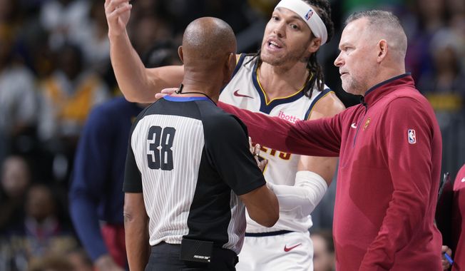 Denver Nuggets forward Aaron Gordon, center, argues after being called for a foul with referee Michael Smith, left, as head coach Michael Malone looks on in the first half of an NBA basketball game against the Golden State Warriors Monday, Dec. 25, 2023, in Denver. (AP Photo/David Zalubowski)