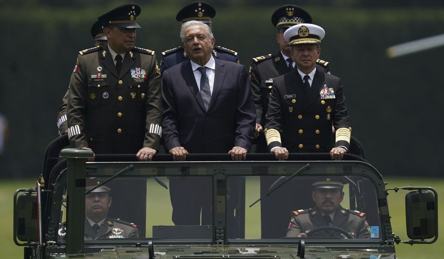 FILE - Mexico&#x27;s President Andres Manuel Lopez Obrador, center, Defense Secretary Luis Cresencio Sandoval, left, and Naval Commander Jose Rafael Ojeda ride in a military vehicle during a parade introducing the new army commander, in Mexico City, Aug. 13, 2021. Mexico launched its army-run airline on Dec. 26, 2023, another role that López Obrador has given to Mexico’s armed forces. (AP Photo/Fernando Llano, File)