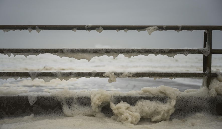 Sea foam is washed over a barrier on Beach Drive in Aptos, Calif., Thursday, Dec. 28, 2023. Powerful surf is rolled onto beaches on the West Coast and Hawaii as a big swell generated by the stormy Pacific Ocean pushes toward shorelines. (AP Photo/Nic Coury)