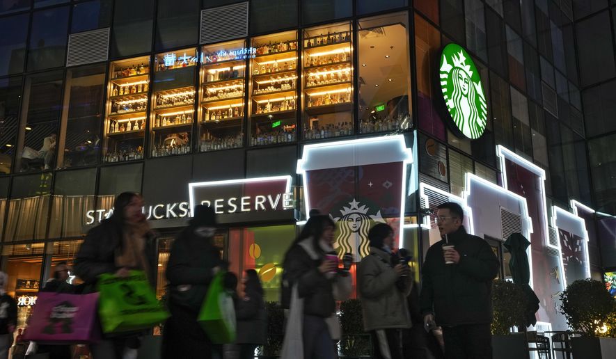 Shoppers walk by a Starbucks cafe at an outdoor shopping mall in Beijing on Saturday, Dec. 23, 2023. (AP Photo/Andy Wong)