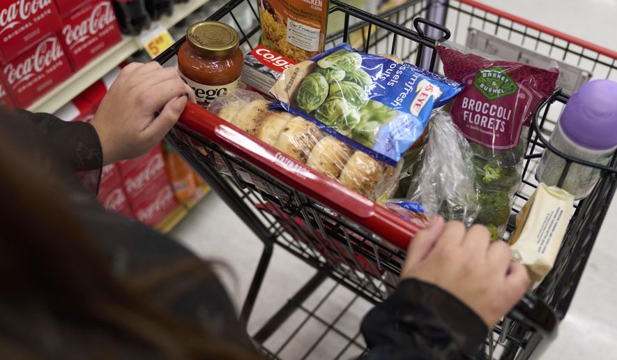 A food shopper pushes a cart of groceries at a supermarket in Bellflower, Calif., on Monday, Feb. 13, 2023. Preparing for a midnight toast and more year-end festivities may require a run or two to the store — but you’ll want to prepare for some limited business hours. (AP Photo/Allison Dinner, File)