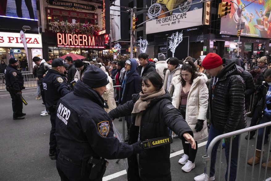 NYPD officers check people ahead of the New Year's Eve in Times Square celebration, Sunday, Dec. 31, 2023, in New York. (AP Photo/Yuki Iwamura)