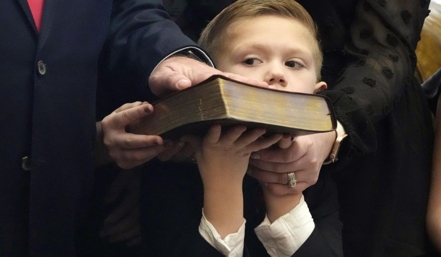 Casper Rhodes, 6, struggles to hold up the family&#x27;s Bible as his father state Sen. Brian Rhodes, R-Pelahatchie, places his hand on the book and recites the oath of office during the swearing in ceremony in the Senate Chamber at the Mississippi State Capitol in Jackson, Miss., Tuesday, Jan. 2, 2024. Both chambers of lawmakers were sworn into the new four-year term that began at noon Tuesday. (AP Photo/Rogelio V. Solis)