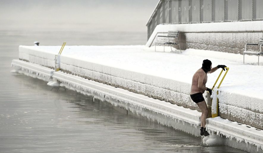 A man climbs out from the icy sea to the pier, in southern Helsinki, Finland, Tuesday, Jan. 2, 2024. Finland and Sweden have recorded this winter’s cold records on Tuesday as a temperatures plummeted to over minus 40 degrees as a result of a cold spell prevailing in the Nordic region. (Vesa Moilanen/Lehtikuva via AP)