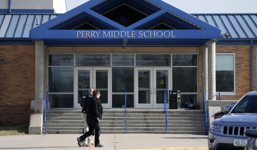 Law enforcement officials walks past the Perry Middle School entrance following a shooting at the nearby Perry High School, Thursday, Jan. 4, 2024, in Perry, Iowa. Multiple people were shot inside the school early Thursday as students prepared to start their first day of classes after their annual winter break, authorities said. (AP Photo/Charlie Neibergall)