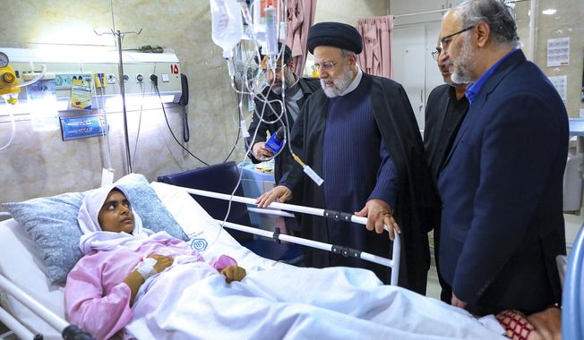 In this photo released by the Iranian Presidency Office, Iranian President Ebrahim Raisi, center, visits a woman who was wounded in Wednesday&#x27;s bomb explosion in the city of Kerman about 510 miles (820 kms) southeast of the capital Tehran, Iran, Friday, Jan. 5, 2024. Iranian officials tried Friday to link Israel and the U.S. to an Islamic State group-claimed suicide bombing, seeking to intertwine the assault with wider Middle East tensions from the Israel-Hamas war. (Iranian Presidency Office via AP)