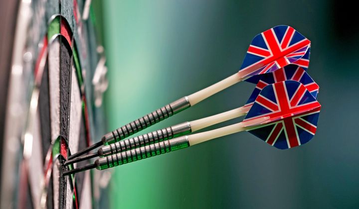 Three darts, with British union flag feathers, stick into the dart board as play continues in the quarterfinals of the World Darts Championship at Alexandra Palace in London, Monday, Jan. 1, 2024. England&#x27;s Deta Hedman refused to play her quarterfinal darts match at this weekend&#x27;s Denmark Open because her opponent, Noa-Lynn van Leuven, is transgender. (AP Photo/Kin Cheung) ** FILE **