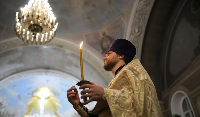 A Russian Orthodox Church priest makes the sign of the cross during an Orthodox Christmas service at the Church of the Holy Martyr Tatiana near the Kremlin Wall in Moscow, Russia, late Saturday, Jan. 6, 2024. (AP Photo/Alexander Zemlianichenko)