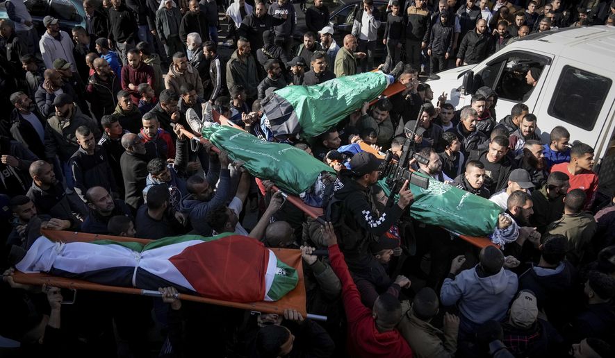 Mourners carry the bodies of six Palestinians, some are draped in the Hamas flags during their funeral in the West Bank city of Jenin on Sunday, Jan. 7, 2024. Six Palestinians and a member of Israel's paramilitary border police were killed in confrontations in a hot spot of violence in the Israeli-occupied West Bank, the Palestinian Health Ministry and the Israeli military said Sunday. (AP Photo/Majdi Mohammed)