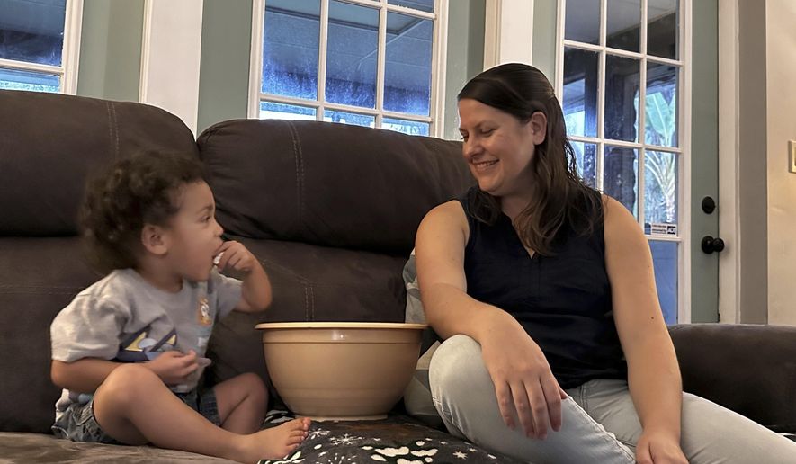 Megan Cherry eats popcorn with her two-year-old son in their home in Temple Terrace, Fla., on Tuesday, Jan. 9, 2024. Cherry is concerned about the ongoing impact of inflation on the grocery budget for her family of six. (AP Photo/Laura Bargfeld)