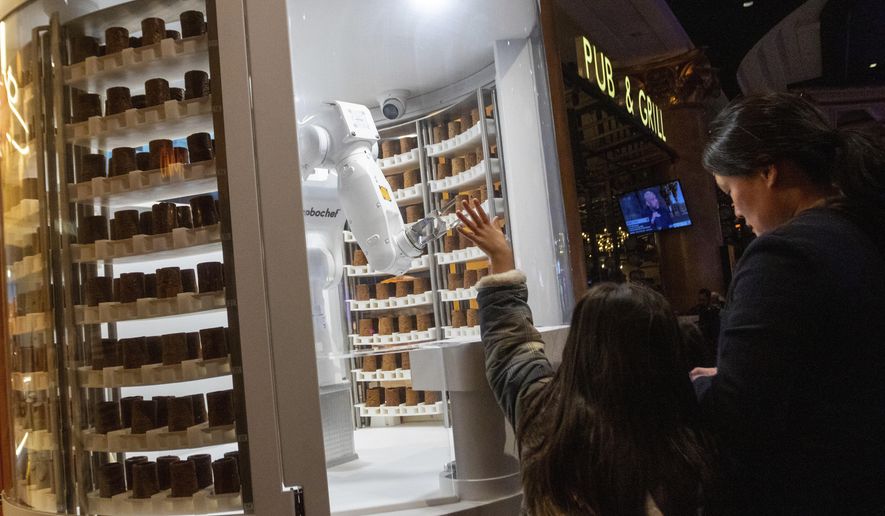 A child waves to a robot dessert booth at Caesars Palace, Thursday, Jan. 11, 2024, in Las Vegas. Chef-like robots and barista bots caused a stir at the annual CES technology trade show in Las Vegas, putting a spotlight on casino union workers' fears that jobs could be at risk in the age of artificial intelligence. (AP Photo/ Ty ONeil) **FILE**