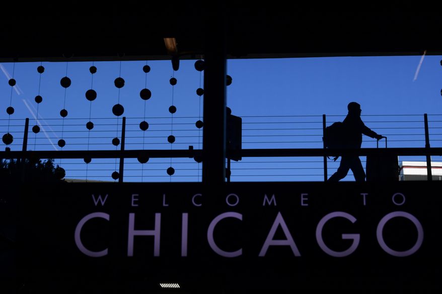 FILE - A passenger walks with luggage past holiday decorations at Chicago O'Hare International Airport, Dec. 24, 2022, in Chicago. (AP Photo/Paul Beaty, File)