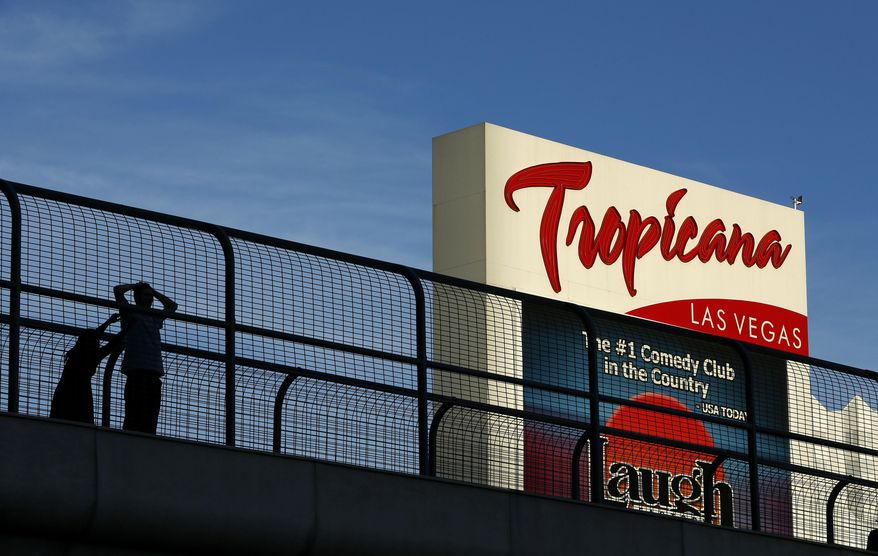 FILE - In this Aug. 4, 2015, photo, people stand on a pedestrian bridge by the Tropicana hotel and casino in Las Vegas. Stopping or standing is prohibited on Las Vegas Strip pedestrian bridges after a new ordinance took effect Tuesday, Jan. 17, 2024. (AP Photo/John Locher, file)