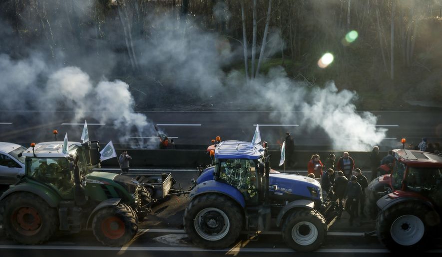 Farmers block a highway near Ableiges, north of Paris, Friday, Jan. 26, 2024. Protesting farmers shut down long stretches of some of France's major motorways on Friday, using their tractors to block and slow traffic and squeeze the government ever more tightly to cede to their demands that growing and rearing food should be made easier and more lucrative. (AP Photo/Thomas Padilla)