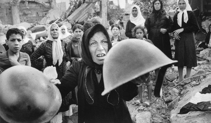 A Palestinian woman brandishes helmets during a memorial service in Beirut September 27, 1982, for victims of Lebanon's Sabra refugee camp massacre. A series of images, including this photo, won the 1983 Pulitzer Prize for spot news photography. Hal Buell, who led The Associated Press' photo operations from the darkroom era into the age of digital photography over a four-decade career with the news organization that included 12 Pulitzer Prizes and some of the defining images of the Vietnam War, has died. He was 92. (AP Photo/Bill Foley, File)