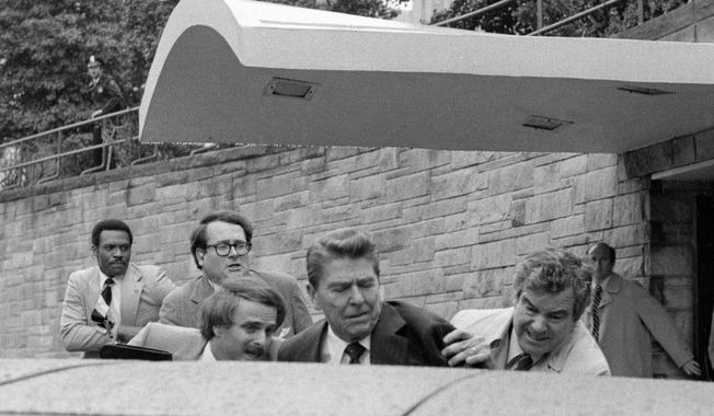 U.S. President Ronald Reagan waves and then looks up before being shoved into the President&#x27;s limousine by secret service agents after being shot outside a Washington hotel Monday, March 30, 1981. A series of images, including this photo, won the 1982 Pulitzer Prize for spot news photography. Hal Buell, who led The Associated Press&#x27; photo operations from the darkroom era into the age of digital photography over a four-decade career with the news organization that included 12 Pulitzer Prizes and some of the defining images of the Vietnam War, has died. He was 92. (AP Photo/Ron Edmonds, File)
