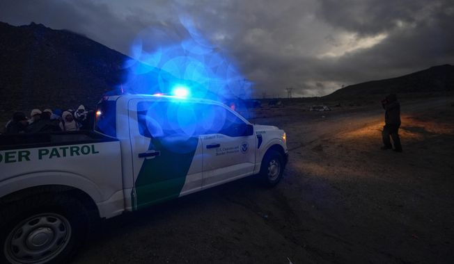 A Border Patrol vehicle parks in front of a group of asylum-seeking migrants as they line up in a makeshift, mountainous campsite to be processed after crossing the border with Mexico, Friday, Feb. 2, 2024, near Jacumba Hot Springs, Calif. (AP Photo/Gregory Bull) ** FILE **