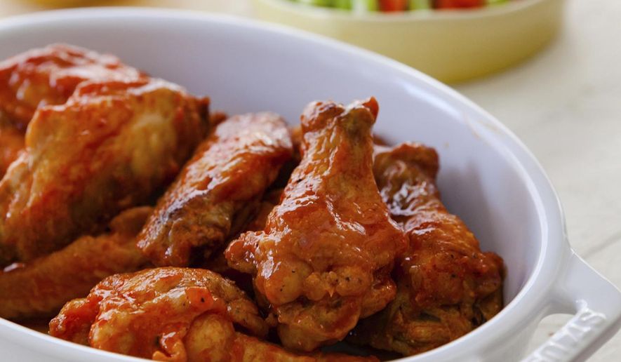 This combination of images shows a recipe for buffalo chicken wings with blue cheese dip and carrot and celery sticks. (Carrie Crow via AP)