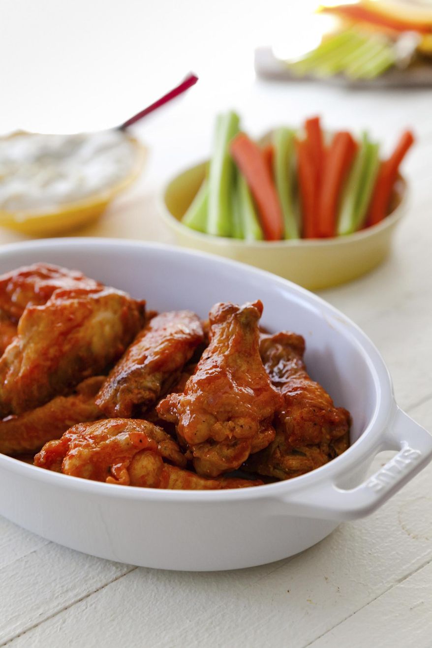 This combination of images shows a recipe for buffalo chicken wings with blue cheese dip and carrot and celery sticks. (Carrie Crow via AP)