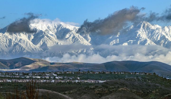 With a break in the cloud cover, the San Gabriel Mountains are covered in snow from the recent storms in an early morning view from the hills in eastern Orange, Calif., on Wednesday, Feb. 7, 2024. (Mark Rightmire/The Orange County Register via AP)
