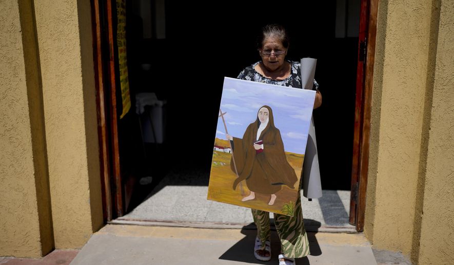 Rita Canteros walks out of a parish church carrying a painting of María Antonia de Paz y Figueroa, more commonly known by her Quechua name of “Mama Antula,” on the outskirts of Buenos Aires, Argentina, Sunday, Jan. 28, 2024. The canonization of “Mama Antula” in a Feb. 11th ceremony to be presided by Pope Francis at St. Peter&#x27;s Basilica marks the first time a female from Argentina will become saint. (AP Photo/Natacha Pisarenko)