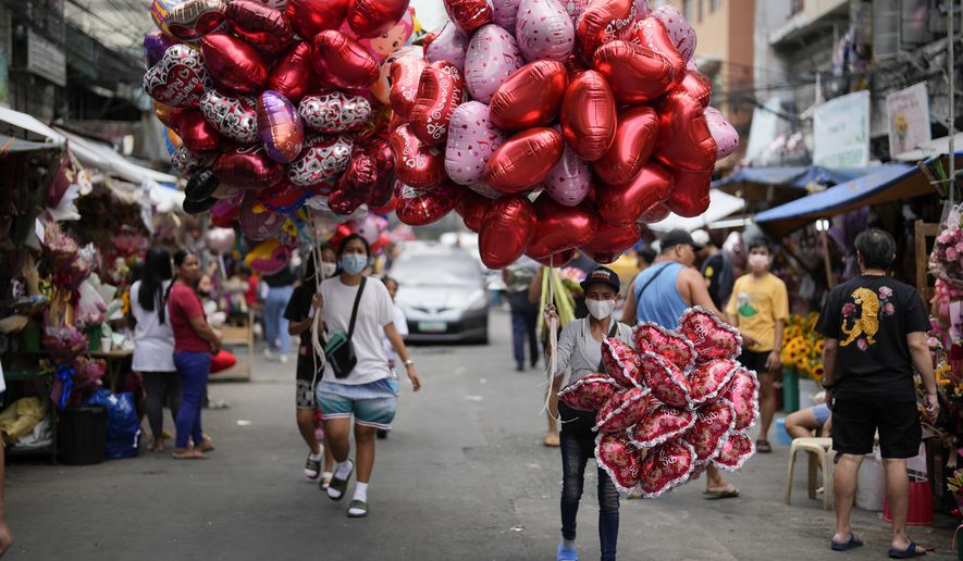 FILE - Women sell heart-shaped balloons at a flower market in Manila, Philippines on Monday, Feb. 13, 2023. Valentine&#x27;s Day is one of those Hallmark holidays that haters call “forced,&quot; too commercialized and downright expensive to pull off if expectations are to be met. (AP Photo/Aaron Favila, File)