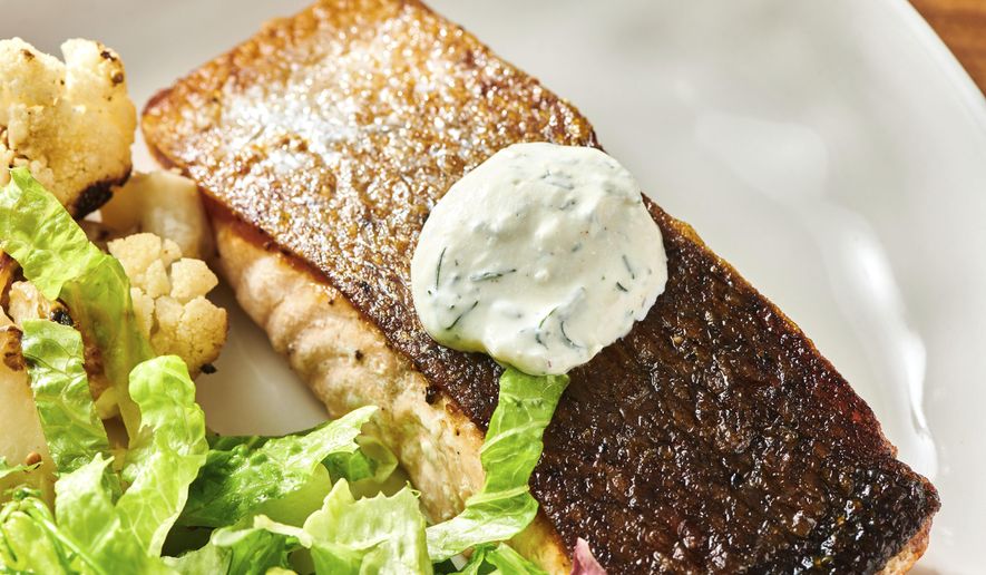 This October 2021 photo shows a recipe for crispy skinned salmon with dill sauce in New York. Pair your fish with a cool and creamy dill sauce and a couple of simple sides, and you have a restaurant-worthy meal in the comfort of home. (Cheyenne Cohen via AP)