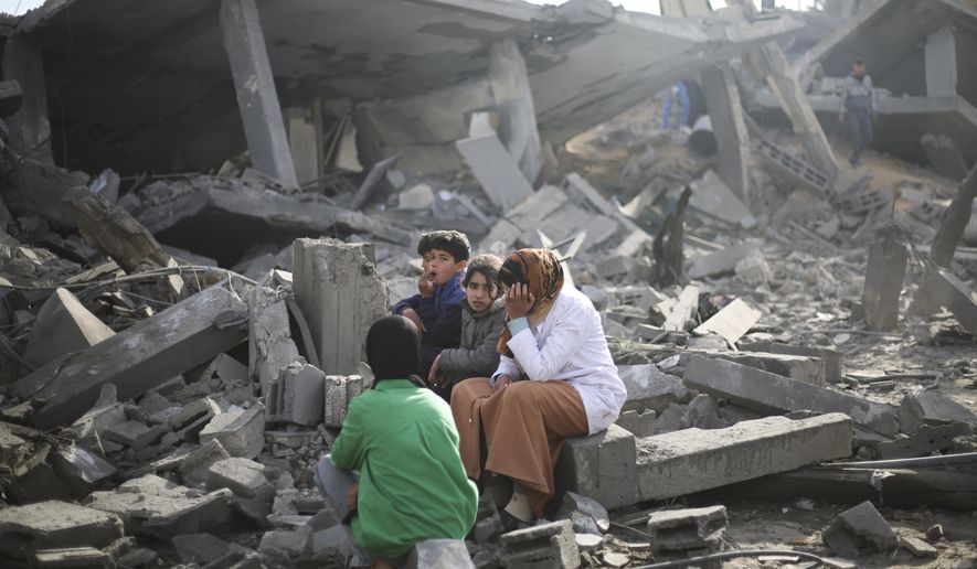 Palestinians sit by the destruction from the Israeli bombardment of the Gaza Strip in Rafah on Monday, Feb. 12, 2024. (AP Photo/Hatem Ali)