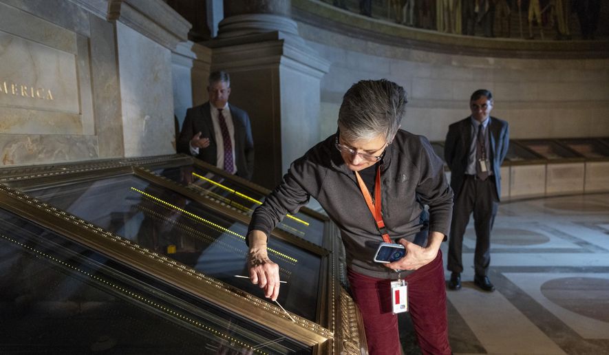 Amy Lubick, a supervisory conservator at the National Archives, runs a cotton swab over a display case that held the U.S. Constitution at National Archives in Washington on Thursday, Feb. 15, 2024. The National Archives building and galleries were evacuated on Feb. 14 after two protesters dumped powder on the protective casing around the U.S. Constitution. (AP Photo/Amanda Andrade-Rhoades)