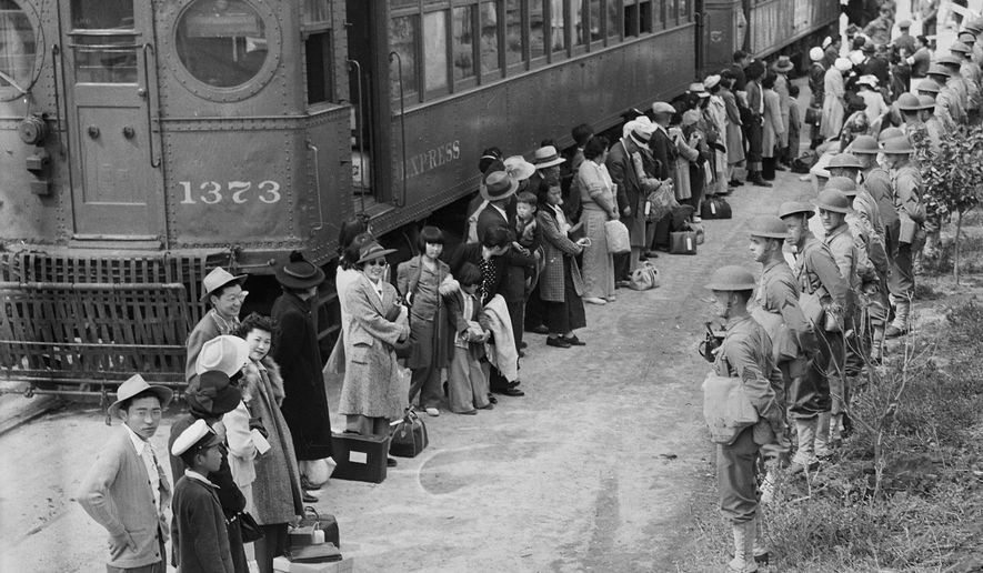 In this photo provided by the National Archives, Japanese Americans from San Pedro, Calif., arrive at the Santa Anita Assembly Center in Arcadia, Calif., on April 5, 1942. People were temporarily housed at this center at the Santa Anita race track before being moved inland to internment camps during World War II. (Clem Albers/War Relocation Authority/National Archives via AP)