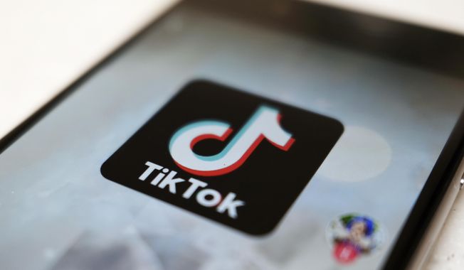 The TikTok logo is displayed on a smartphone screen, Sept. 28, 2020, in Tokyo, Japan. The European Union is looking into whether TikTok has broken the bloc’s strict new digital rules for cleaning up social media and keeping internet users safe. (AP Photo/Kiichiro Sato, File)