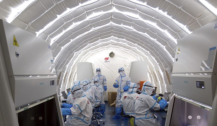 In this file photo released by China's Xinhua News Agency, staff members work in an inflatable COVID-19 testing lab provided by Chinese biotech company BGI Genomics, a subsidiary of BGI Group, in Beijing on June 23, 2020. (Chen Zhonghao/Xinhua via AP) **FILE**