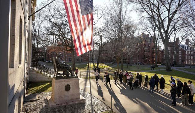 People take photos near a John Harvard statue, left, on the Harvard University campus, Jan. 2, 2024, in Cambridge, Mass. In a letter Monday, Feb. 19, to the school community, Harvard University condemned what it called a “flagrantly antisemitic cartoon” posted on social media over the weekend by a group that includes students and faculty. (AP Photo/Steven Senne, File)