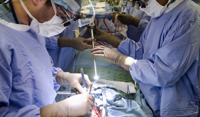 In this Tuesday, Jan. 23, 2018, photo, a surgeon directs a special camera to be able to view his patient&#x27;s cancer tumor on monitors while performing surgery at a hospital in Philadelphia. As the COVID-19 coronavirus spreads, many cancer surgeries are being delayed, stent procedures for clogged arteries have been pushed back and infertility specialists were asked to postpone helping patients get pregnant. In March 2020, doctors in virtually every field are scrambling to alter care. (AP Photo/Matt Rourke) **FILE**