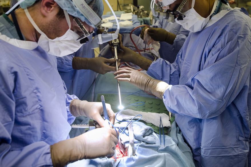 In this Tuesday, Jan. 23, 2018, photo, a surgeon directs a special camera to be able to view his patient's cancer tumor on monitors while performing surgery at a hospital in Philadelphia. As the COVID-19 coronavirus spreads, many cancer surgeries are being delayed, stent procedures for clogged arteries have been pushed back and infertility specialists were asked to postpone helping patients get pregnant. In March 2020, doctors in virtually every field are scrambling to alter care. (AP Photo/Matt Rourke) **FILE**
