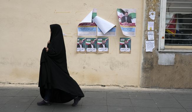 A woman walks past electoral posters of candidates for the March 1, parliamentary election, in downtown Tehran, Iran, Thursday, Feb. 22, 2024. Candidates for Iran&#x27;s parliament began campaigning Thursday in the country&#x27;s first election since the bloody crackdown on the 2022 nationwide protests that followed the death of 22-year-old Mahsa Amini in police custody. (AP Photo/Vahid Salemi)