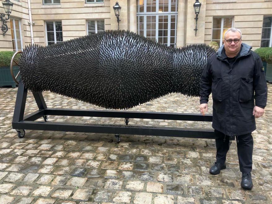 Ukraine's Mikhail Reva poses next to one of his art pieces, Thursday, Feb. 22, 2024 in Paris. From within the debris of Russia's war, Ukraine's most famous sculptor was compelled to take a dark artistic pivot and express his homeland's suffering the day his own country house was ravaged by a Russian strike. (AP Photo/Thomas Adamson